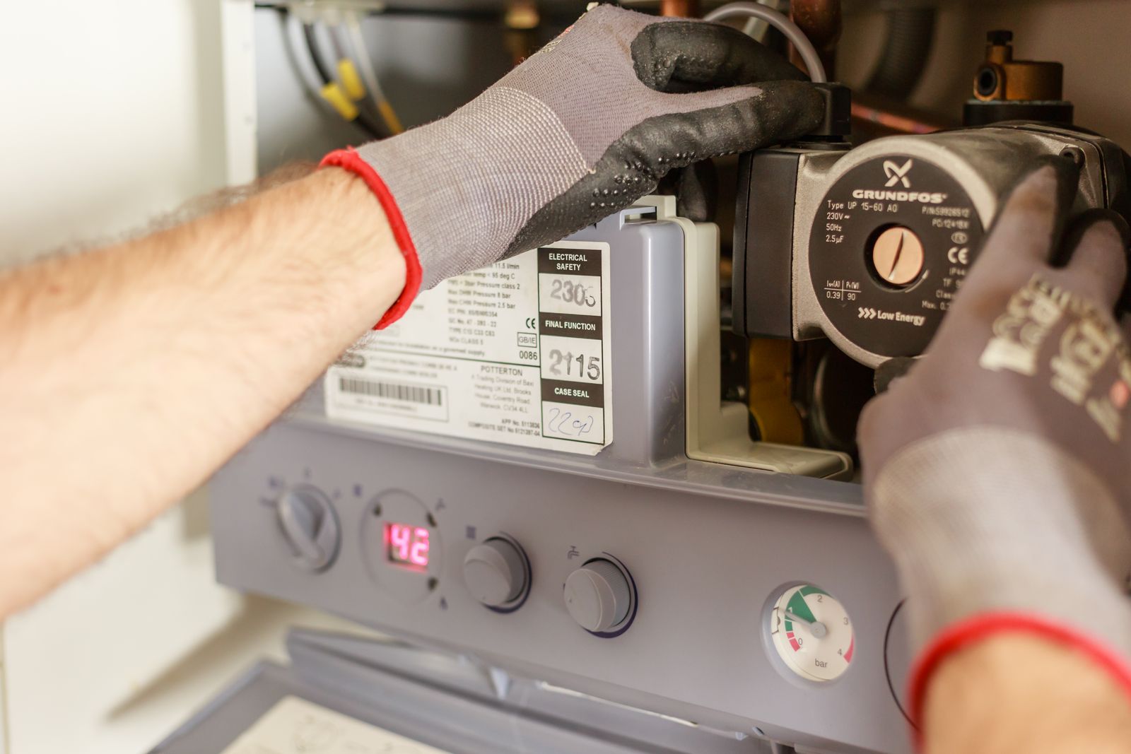 Gloved hands adjusting a heating system during service (stock photo by Heiko Ruth via Pexels)